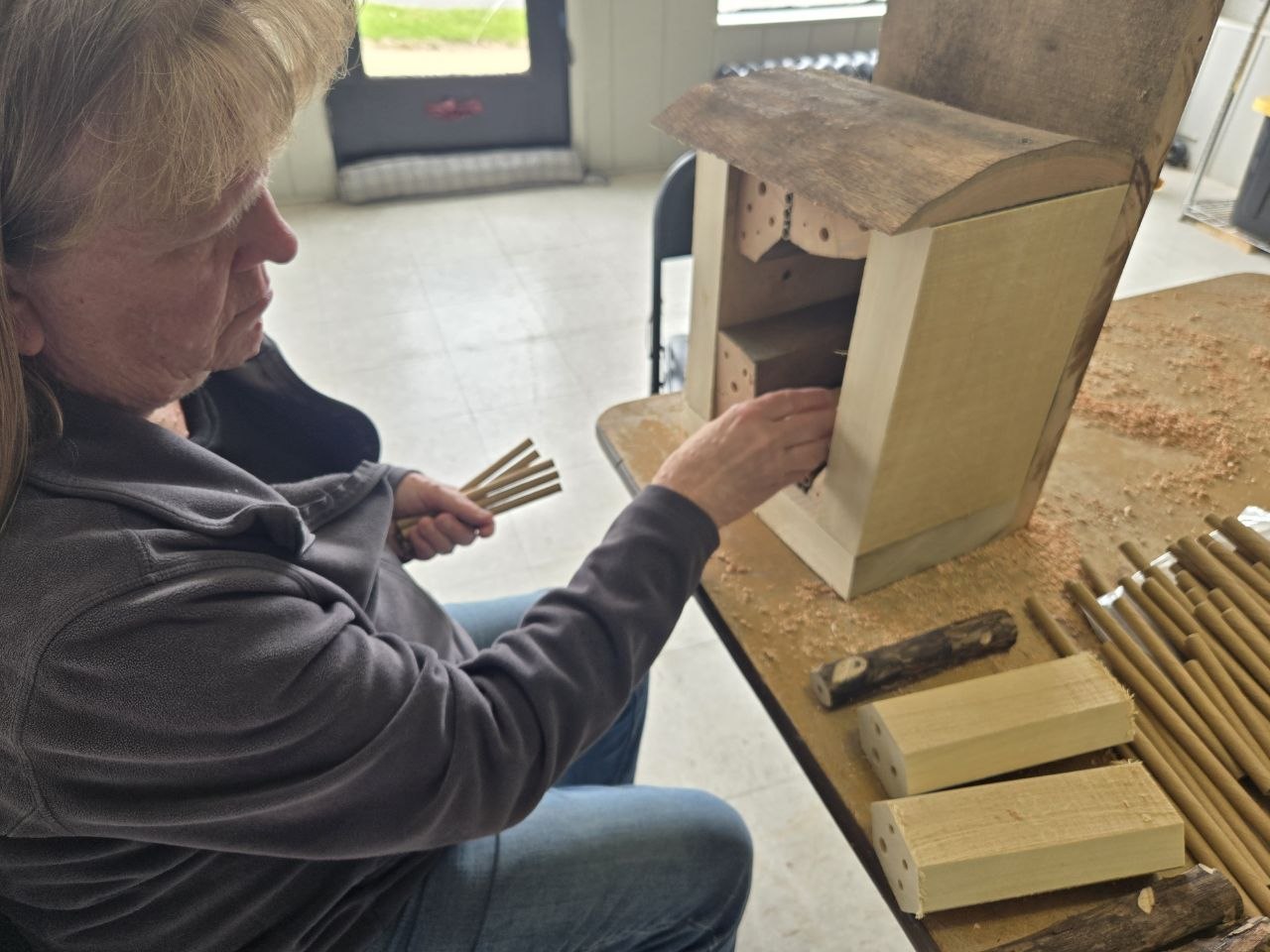 Continuing to arrange the interior of the rustic backyard bee hotel
