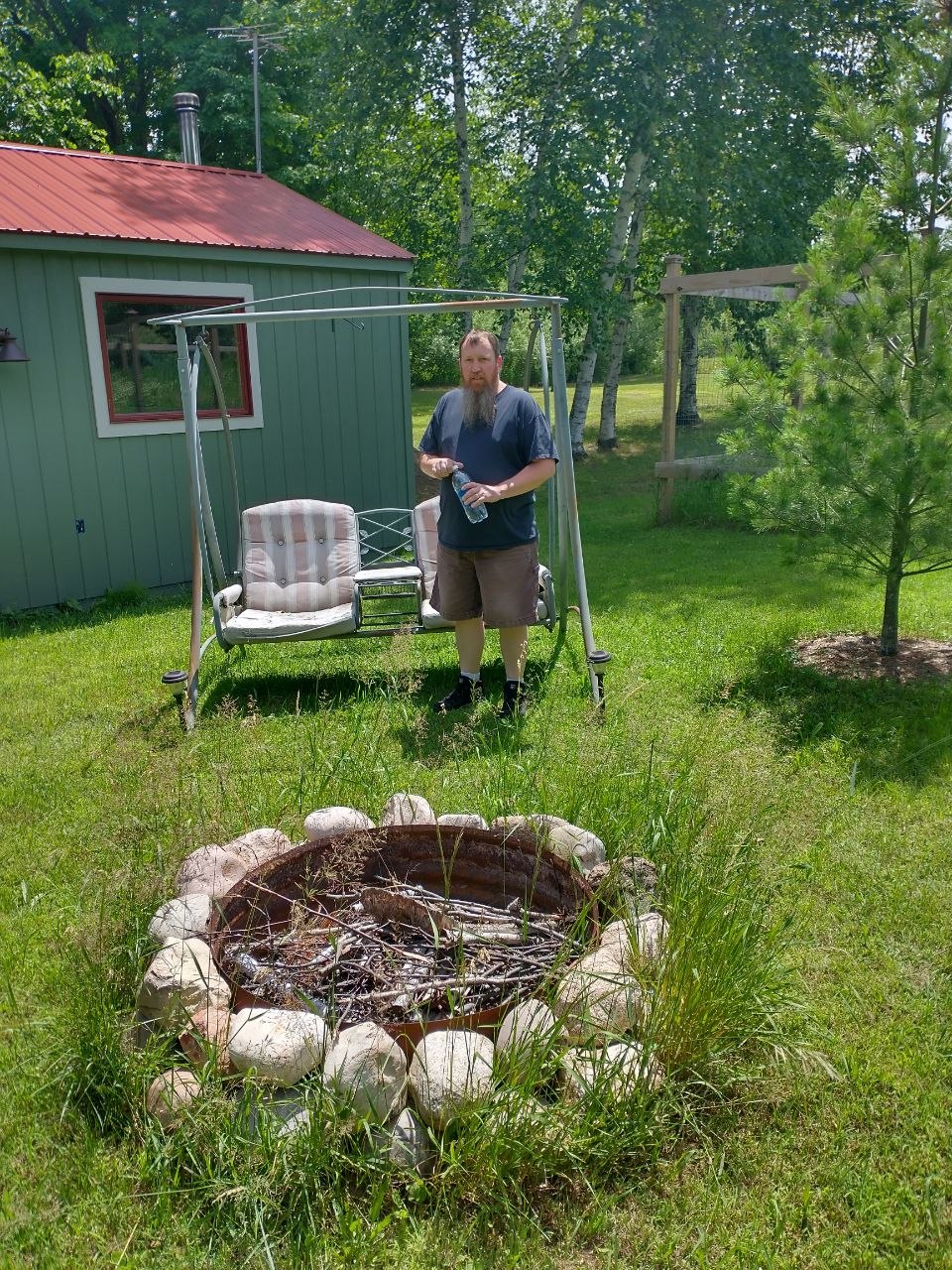 Jeff standing by swing and fire ring at the cabin property