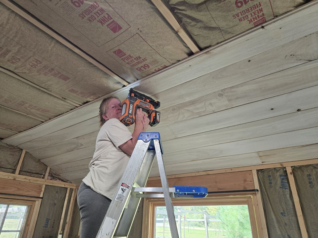 Vanessa helping with the cabin ceiling project with insulation visible overhead