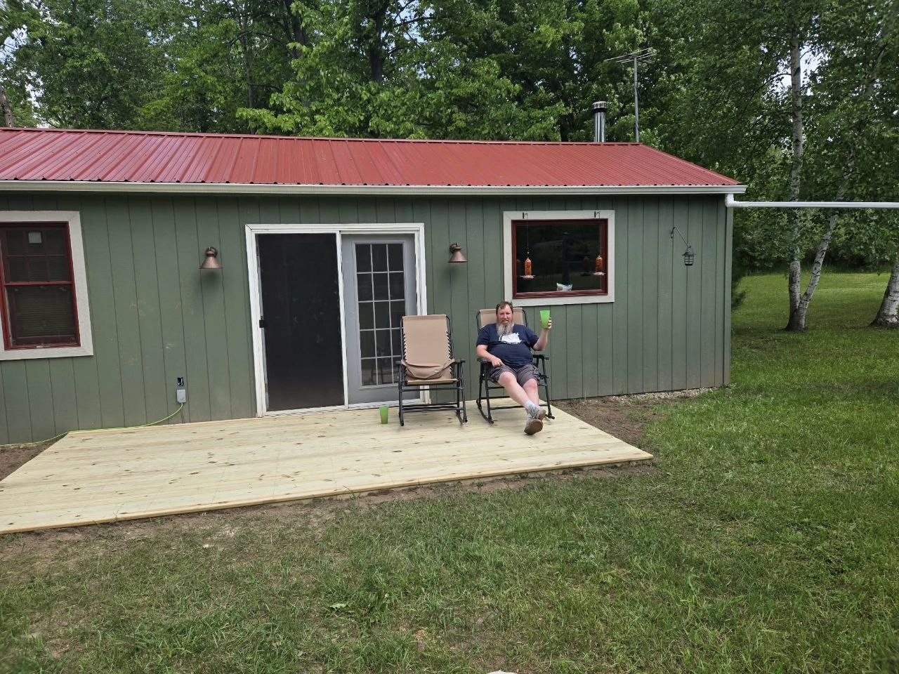 Finished deck with chairs out and Jeff relaxing beside the cabin after the build was complete