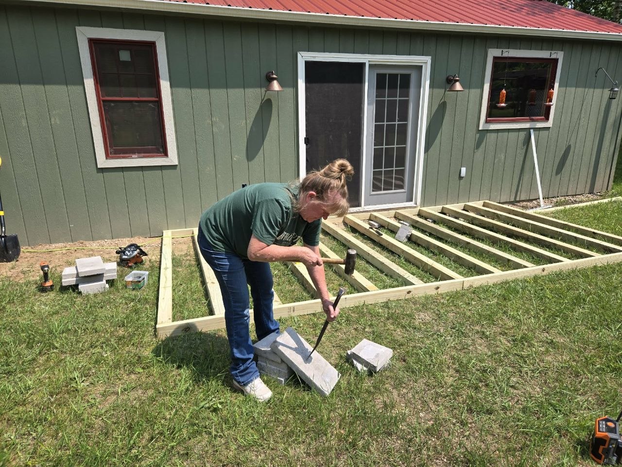 Vanessa helping with the deck frame build beside the cabin doors during the 2025 deck project