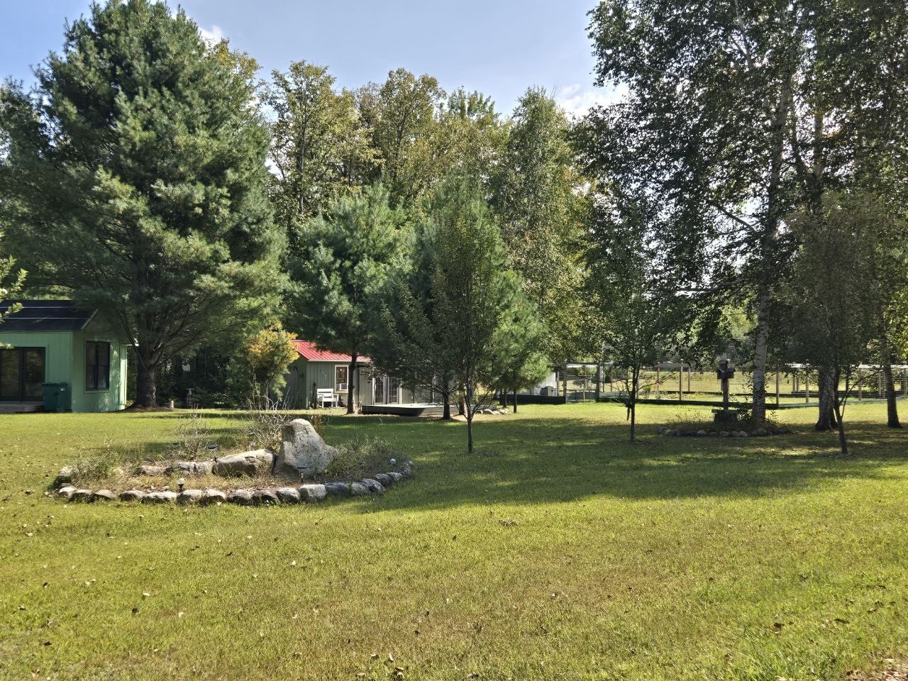 Wide payoff view of the cabin, green structure, deck, and garden area showing how far the property had come by fall 2025