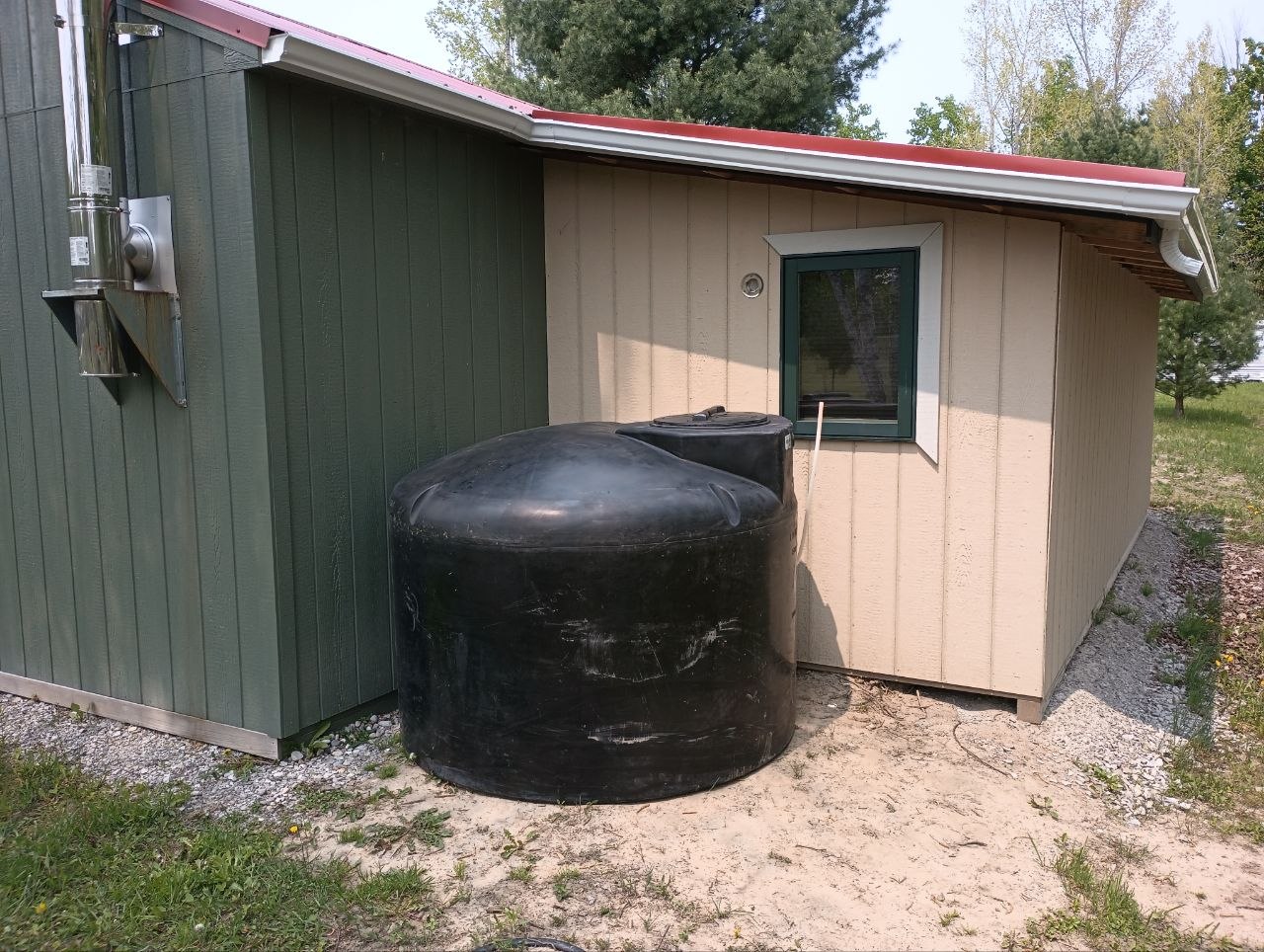 Metal roof installed, gutters installed, and the new 500 gallon water tank placed beside the cabin