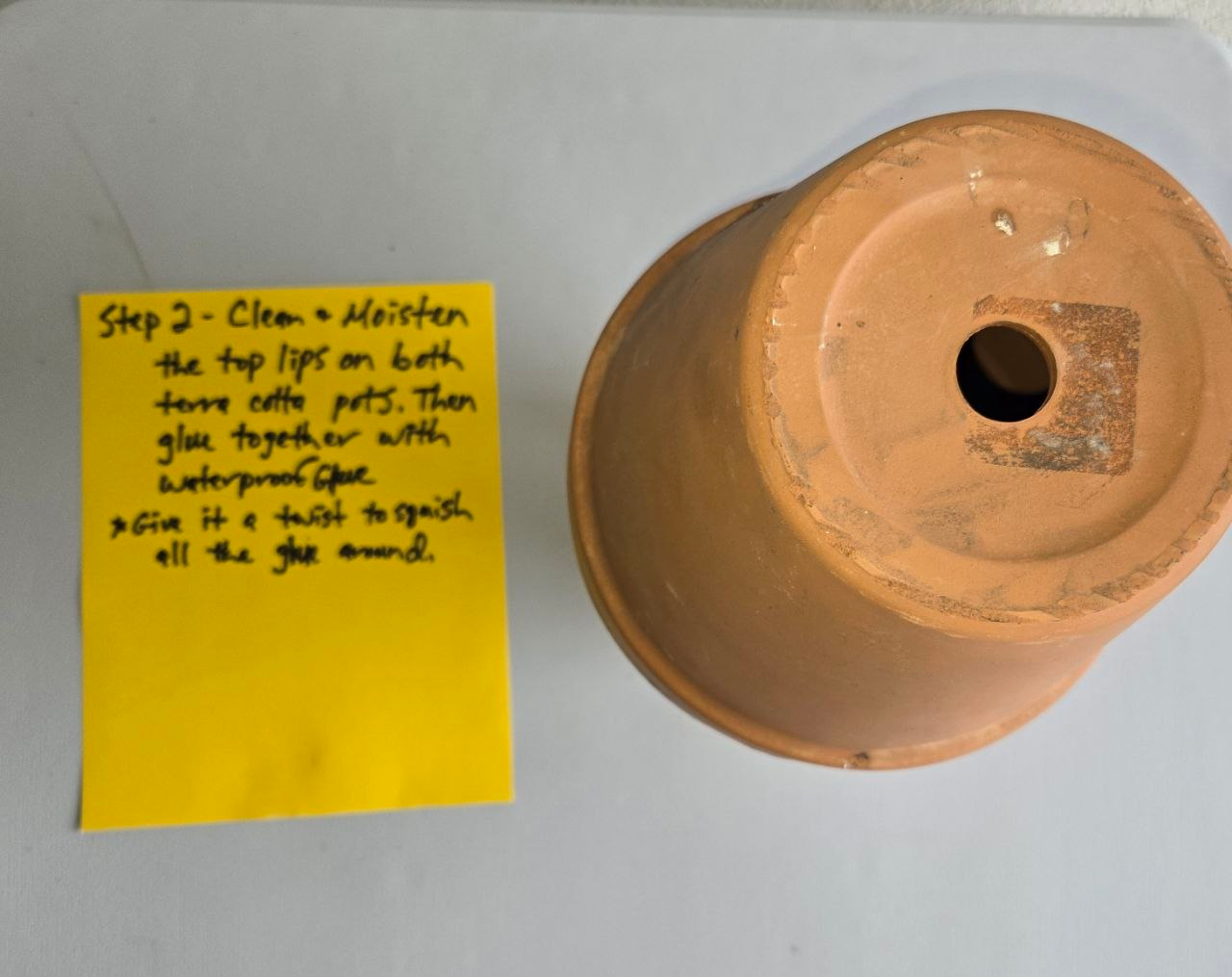 Adding adhesive to join the two terracotta pots